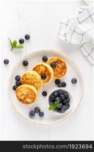 Cottage cheese or curd fritters with honey and fresh blueberry. Healthy diet food, breakfast. Top view.