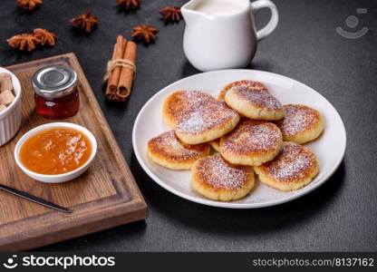 Cottage cheese pancakes on a black concrete background. Cottage cheese pancakes with oats, syrniki on a black rustic background