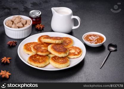 Cottage cheese pancakes on a black concrete background. Cottage cheese pancakes with oats, syrniki on a black rustic background