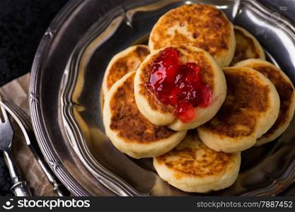 Cottage cheese pancakes with currant jam, closeup, top view
