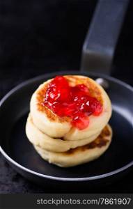 Cottage cheese pancakes with currant jam in pan, selective focus