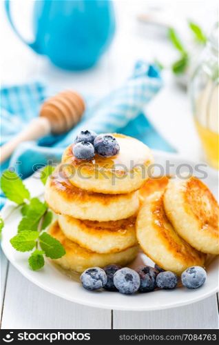 Cottage cheese pancakes with honey and blueberry on white background, breakfast or lunch