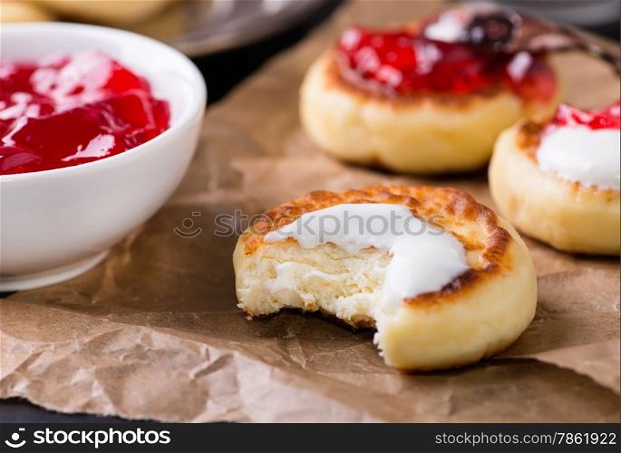 Cottage cheese pancakes with sour cream and currant jam, closeup, selective focus
