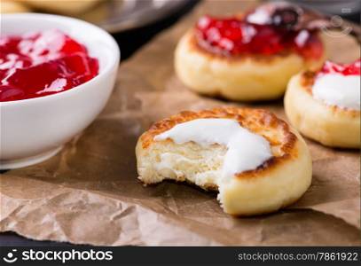 Cottage cheese pancakes with sour cream and currant jam, closeup, selective focus
