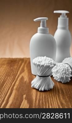 cotton swabs and bottles on wooden board
