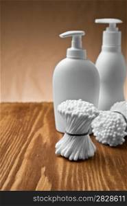 cotton swabs and bottles on wooden board