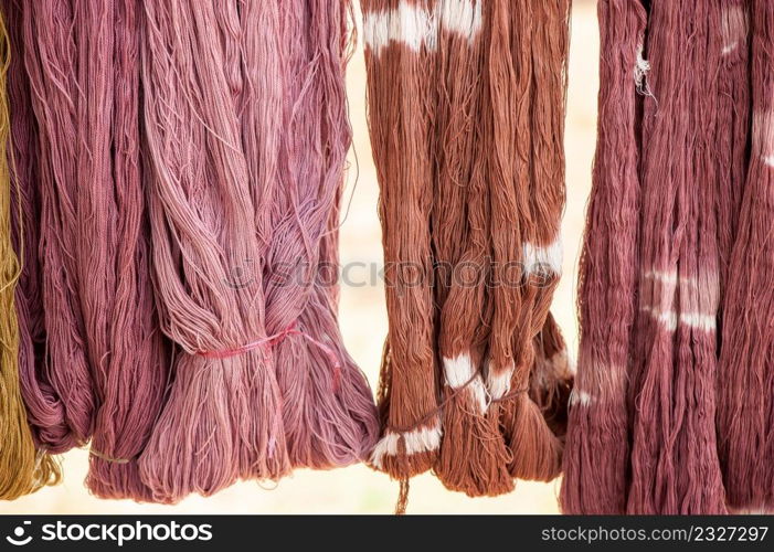 Cotton yarn dyeing with the natural dyes hanging in sunlight for drying. Local handmade products of Sakon Nakhon Province, Northeast Thailand. Culture, local wisdom.