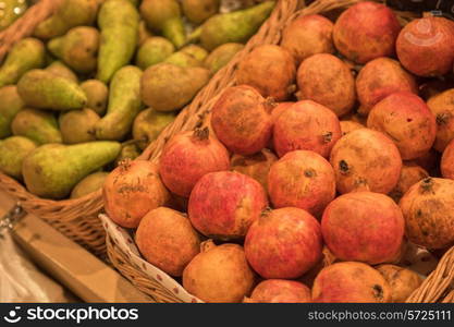 Counter with ripe pomegranates and pears in supermarket