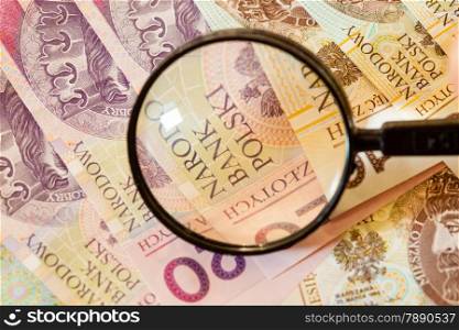 Counterfeit money concept. Polish zloty banknotes currency and magnifying glass
