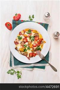 Country egg omelette in white plate with tomatoes,bread, cheese and sausage on wooden background, top view