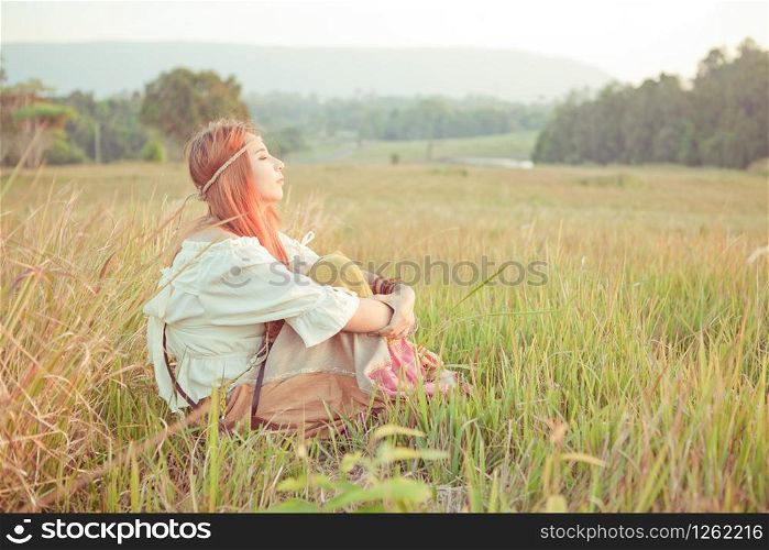 Country hippie girl sitting at golden field
