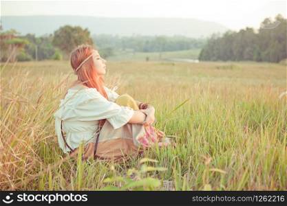 Country hippie girl sitting at golden field