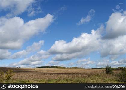 Country landscape, plowed farm field, white clouds in the sky