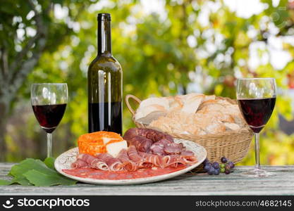 Country life setting with wine, fruits, cheese and meat. Outdoor