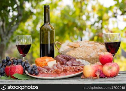 Country life setting with wine, fruits, cheese and meat. Outdoor