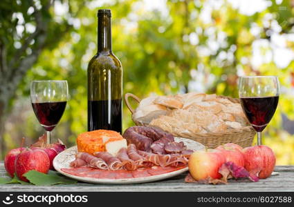 Country life setting with wine, fruits, cheese and meat. Outdoor