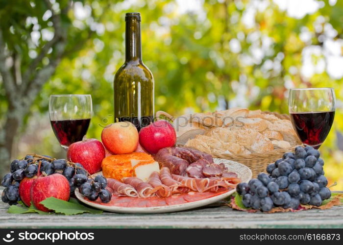 Country life setting with wine, fruits, cheese and meat. Outdoor