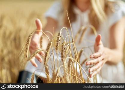 country, nature, summer holidays, agriculture and people concept - close up of young woman hands touching spikelets in cereal field