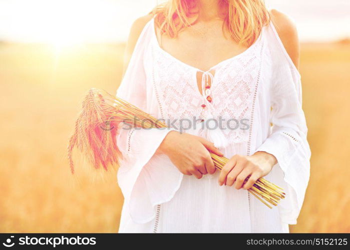 country, nature, summer holidays, vacation and people concept - close up of smiling young woman in white dress with spikelets on cereal field. close up of happy woman with cereal spikelets