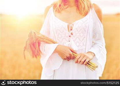 country, nature, summer holidays, vacation and people concept - close up of smiling young woman in white dress with spikelets on cereal field. close up of happy woman with cereal spikelets