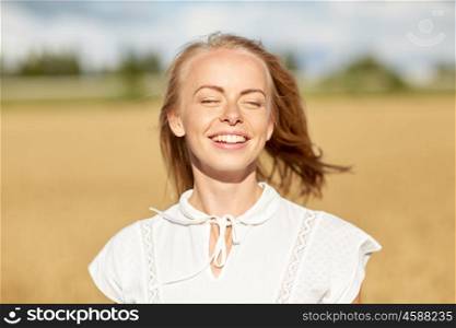 country, nature, summer holidays, vacation and people concept - happy smiling young woman or teenage girl in white enjoying sun on cereal field
