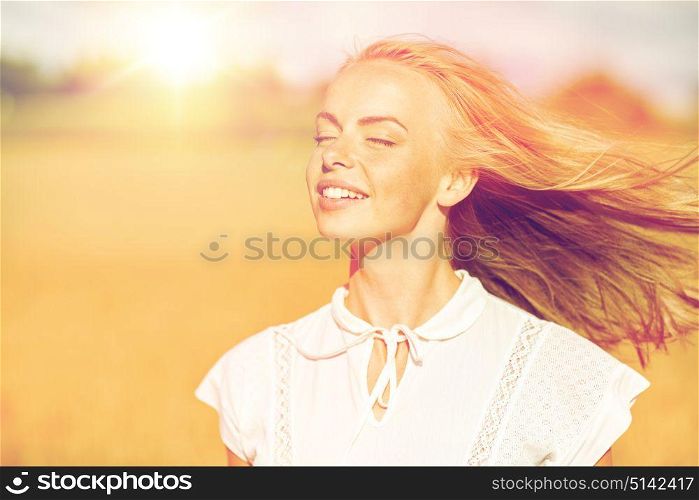 country, nature, summer holidays, vacation and people concept - happy smiling young woman or teenage girl in white enjoying sun on cereal field. smiling young woman in white on cereal field
