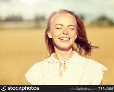 country, nature, summer holidays, vacation and people concept - happy smiling young woman or teenage girl in white enjoying sun on cereal field. smiling young woman in white on cereal field