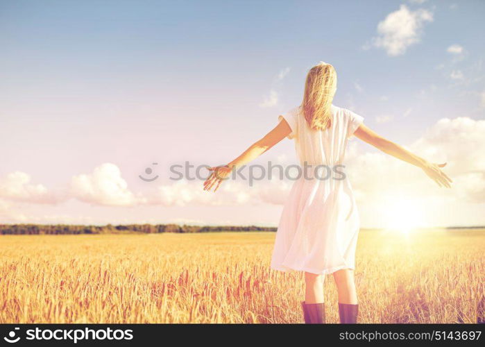 country, nature, summer holidays, vacation and people concept - happy young woman in white dress on cereal field. happy young woman in white dress on cereal field