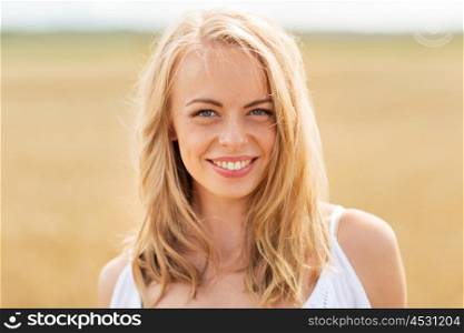 country, nature, summer holidays, vacation and people concept - smiling young woman in white on cereal field