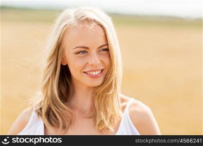 country, nature, summer holidays, vacation and people concept - smiling young woman in white on cereal field