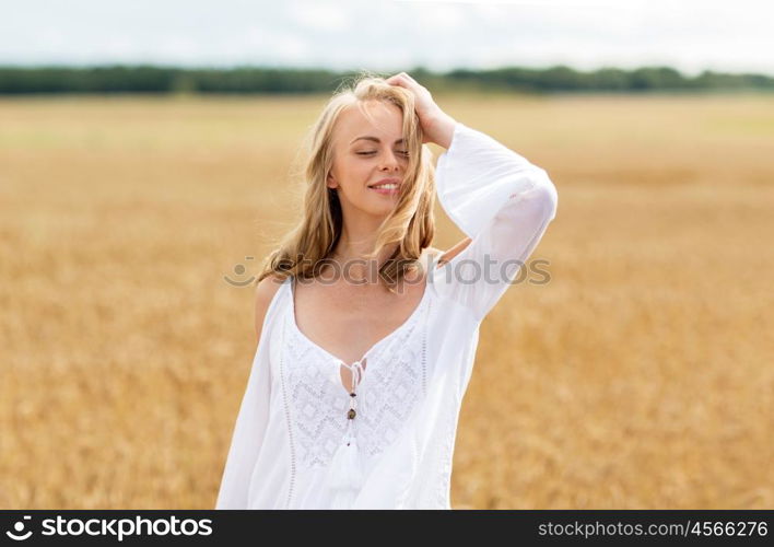 country, nature, summer holidays, vacation and people concept - smiling young woman in white dress on cereal field