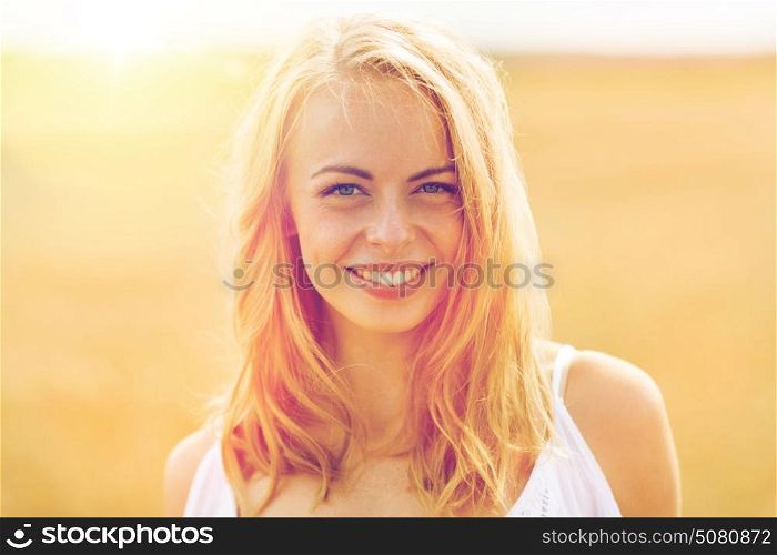 country, nature, summer holidays, vacation and people concept - smiling young woman in white on cereal field. smiling young woman in white on cereal field