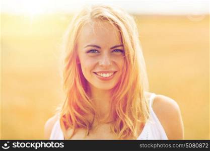 country, nature, summer holidays, vacation and people concept - smiling young woman in white on cereal field. smiling young woman in white on cereal field
