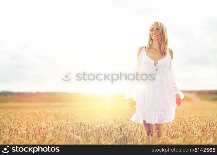 country, nature, summer holidays, vacation and people concept - smiling young woman in white dress on cereal field. smiling young woman in white dress on cereal field