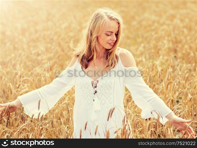 country, nature, summer holidays, vacation and people concept - smiling young woman in white dress on cereal field. smiling young woman in white dress on cereal field
