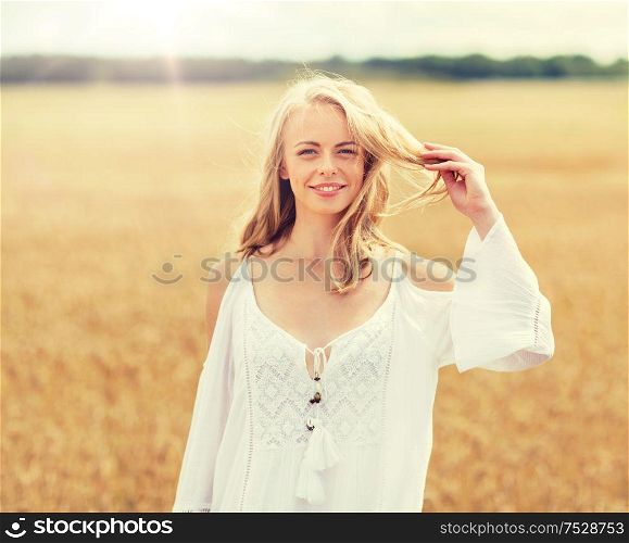 country, nature, summer holidays, vacation and people concept - smiling young woman in white dress on cereal field. smiling young woman in white dress on cereal field
