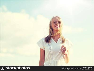 country, nature, summer holidays, vacation and people concept - smiling young woman in white dress over blue sky. smiling young woman in white dress over blue sky