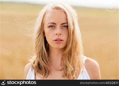 country, nature, summer holidays, vacation and people concept - young woman in white on cereal field