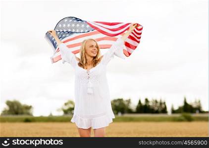 country, patriotism, independence day and people concept - happy smiling young woman in white dress with national american flag on cereal field