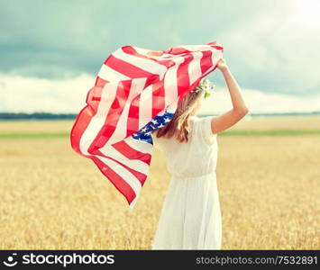 country, patriotism, independence day and people concept - happy young woman in white dress with national american flag on cereal field. happy woman with american flag on cereal field