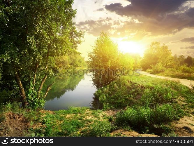 Country road near river in sunny evening