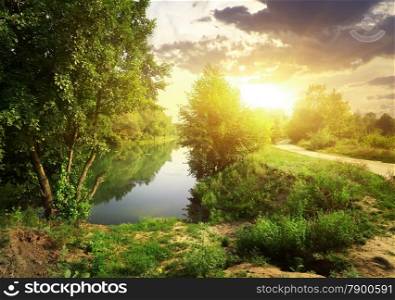 Country road near river in sunny evening