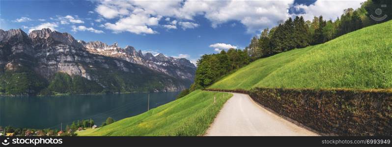 Country road near Walensee lake and the Alps mountains on a sunny day of spring, in Switzerland, in St. Gallen Canton. Summer nature and hiking path.