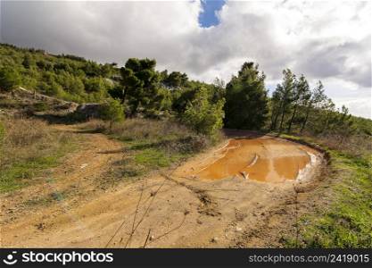 Country road with mud at Penteli mountain at Attica, Greece. Mount Penteli is a mountain in Attica, Greece, situated northeast of Athens and southwest of Marathon.. Country road with mud at Penteli mountain at Attica, Greece.