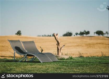 Country Tourism Lounge Chairs Landscape. A relaxing country scene in Alentejo, Portugal, with a fantastic landscape view. Includes two lounge chairs and a small tree trunk.