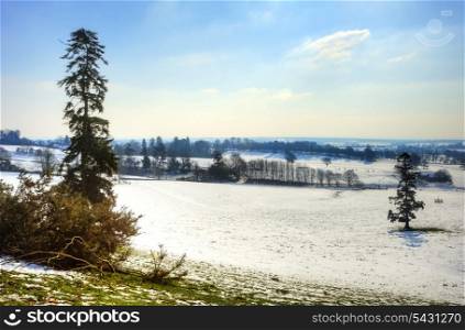 Countryside landscape across rural setting with Winter snow on ground and bright blue sky background
