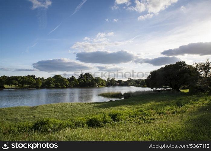 Countryside landscape over fields to calm lake wth blue sky