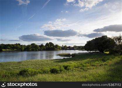 Countryside landscape over fields to calm lake wth blue sky