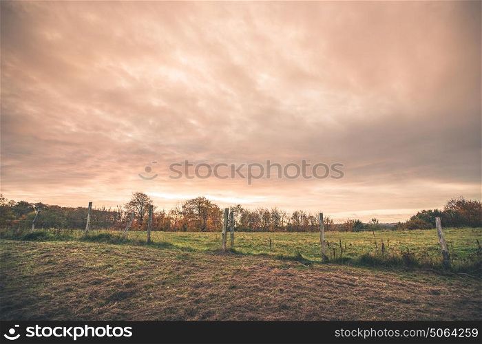 Countryside landscape with a wired fence on a field in the sunset in a rural environment
