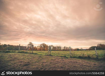 Countryside landscape with a wired fence on a field in the sunset in a rural environment